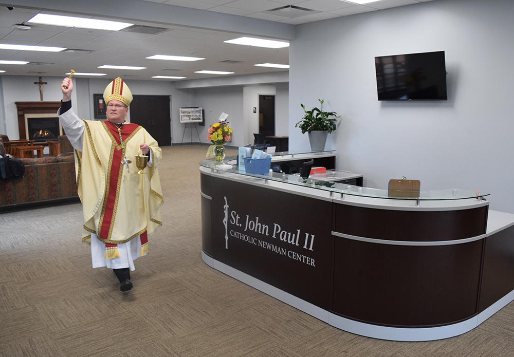 Bishop Louis Tylka blesses the lounge and reception desk at the newly renovated St. John Paul II Catholic Newman Center in Normal during ceremonies on Oct. 22. (The Catholic Post/Tom Dermody)